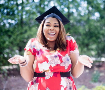 Young woman smiling in a dress with graduation cap