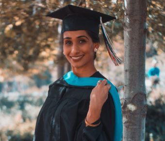 young girl smiling while wearing graduation cap and gown